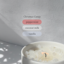 Large stoneware candle, lit, it’s top covered in rock salt. The title reads “Christmas Candy”, and underneath is the scent profile: peppermint, coconut milk, vanilla.