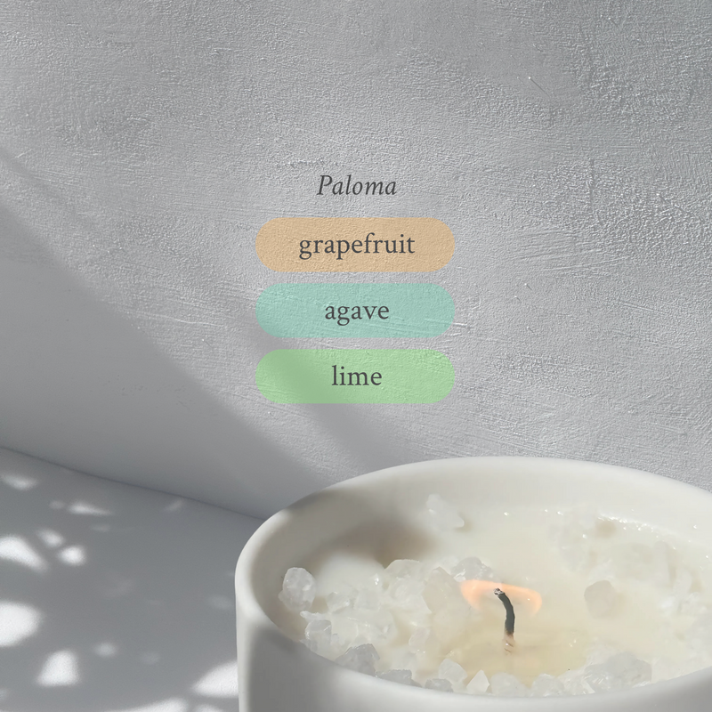 Large stoneware candle, lit, it’s top covered in rock salt. The title reads “Paloma”, and underneath is the scent profile: grapefruit, agave, lime.