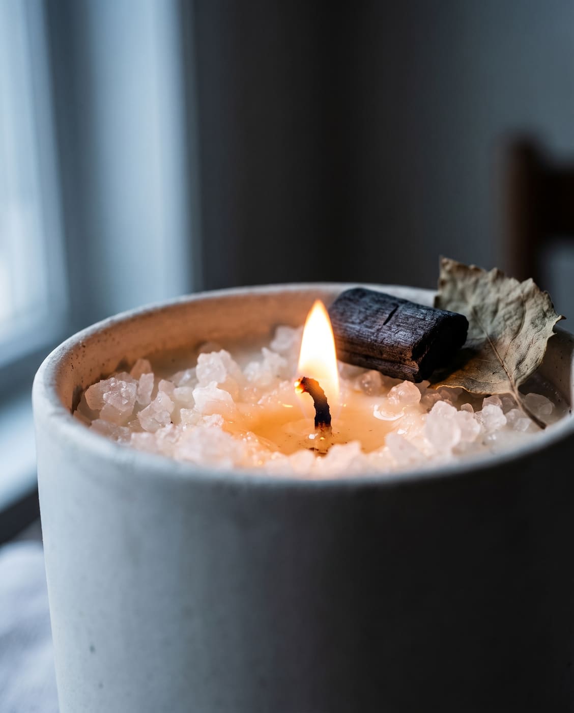 Close-up of Black Sand candle, charcoal and dried leaf on sea salt crystals